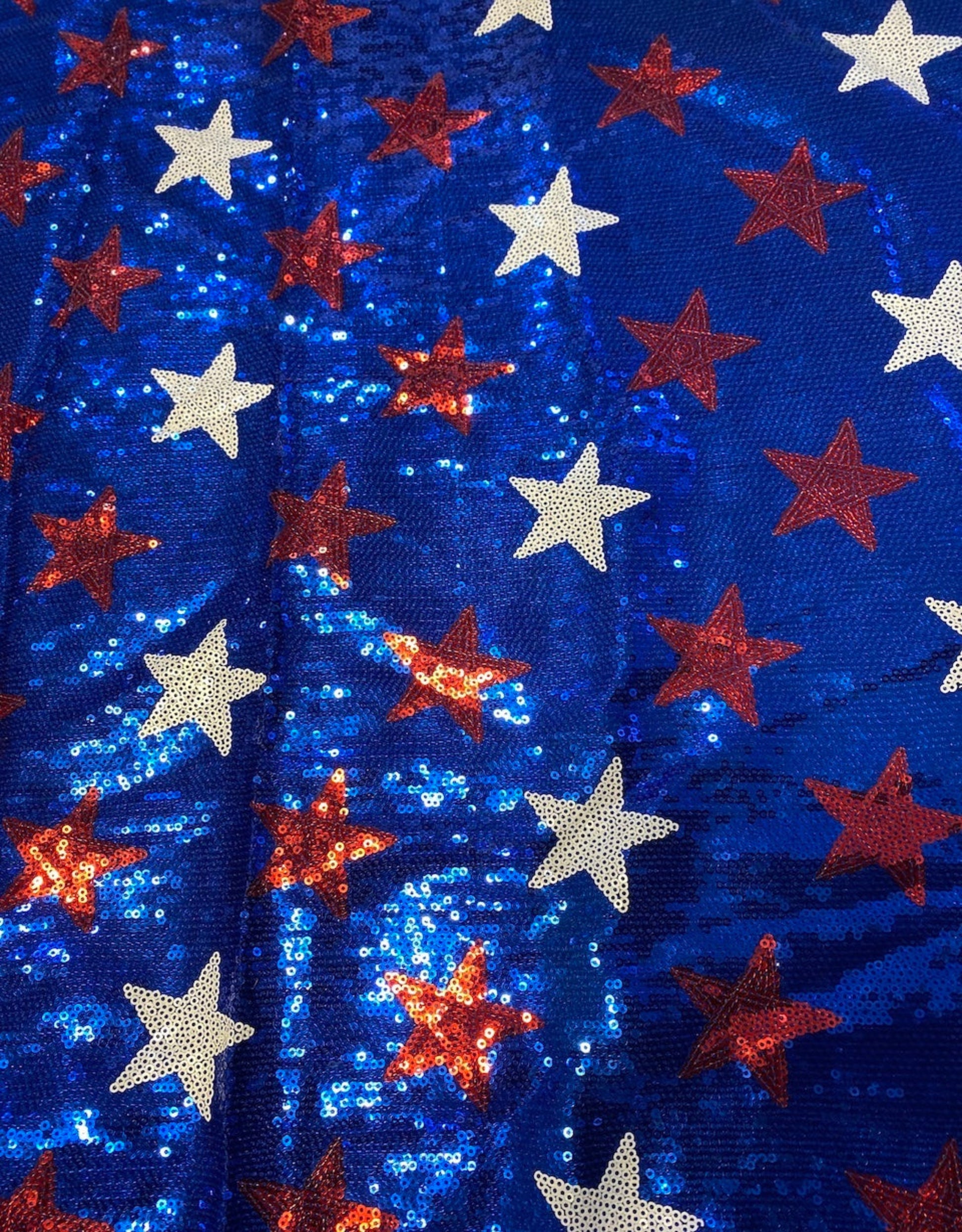 Sequined fabric with red, white, and blue stars on a blue background